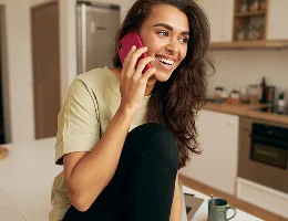 شابة تبتسم أثناء التحدث على الهاتف في المنزل